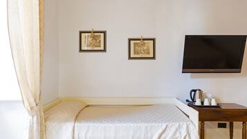 A hotel room with a bed, a flat-screen TV, and two framed pictures on the wall.