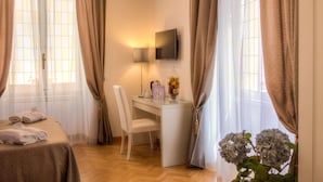 A hotel room with a bed, desk, chair, and a potted plant. - Relais Calamatta (Rome)