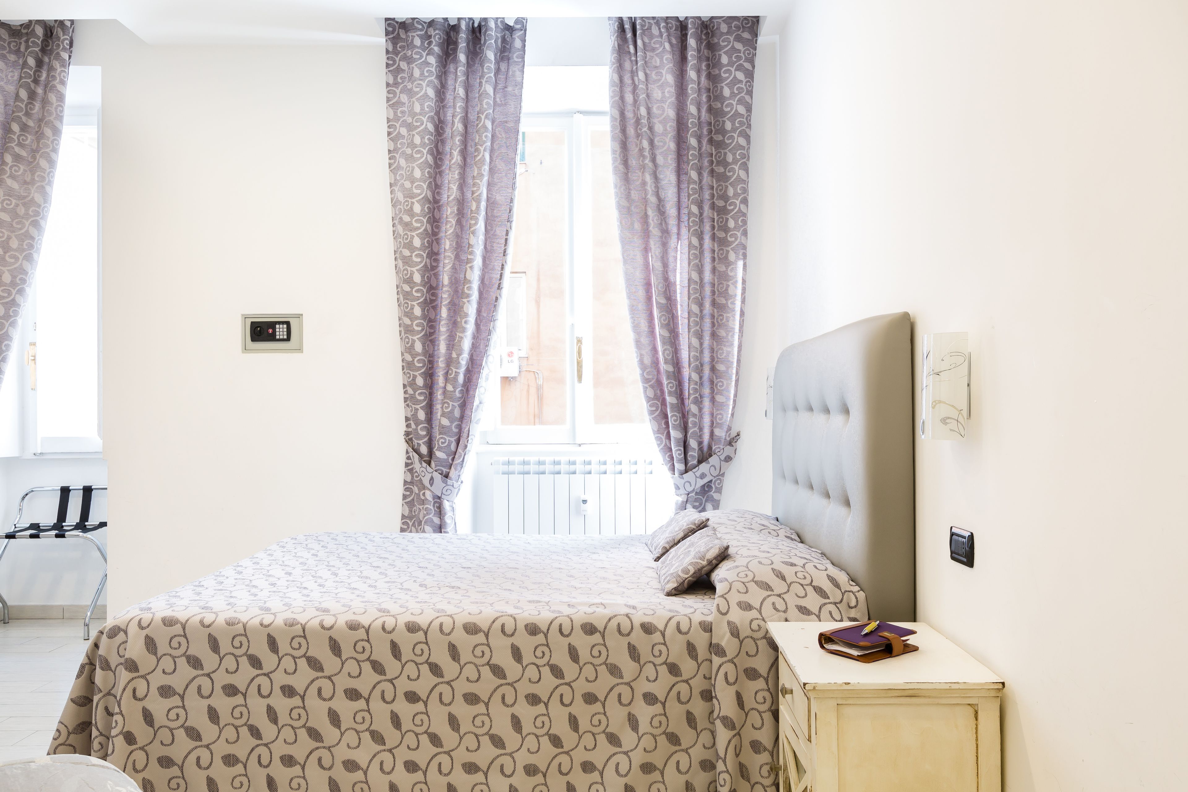 Una camera da letto con un letto, tende, un comodino e vista sull'esterno.