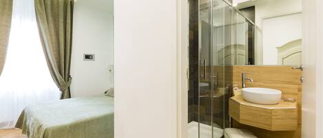 Une chambre à coucher moderne avec un lit, une salle de bain dotée d’une douche en verre et une coiffeuse en bois.