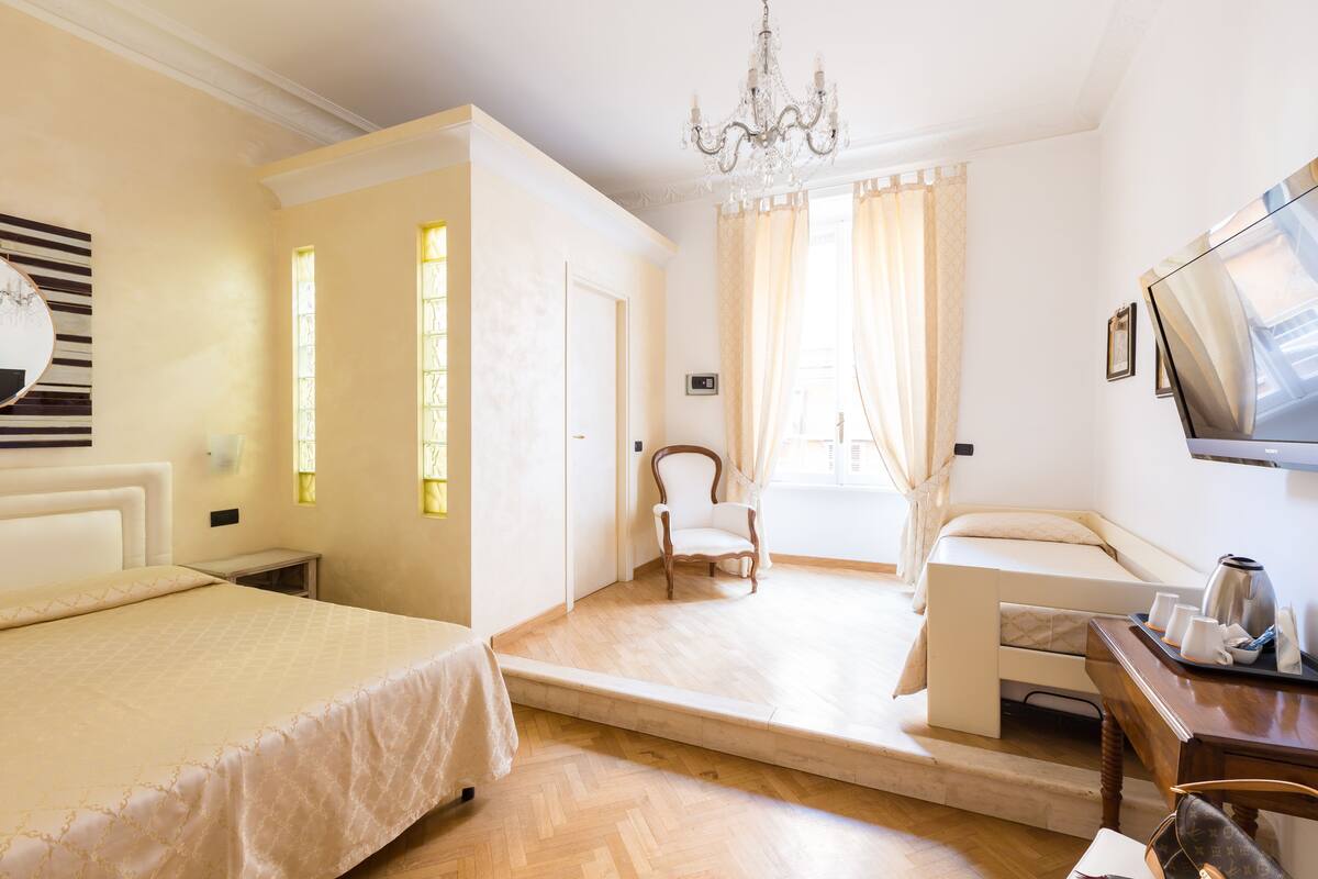A hotel room with a bed, a chair, a sofa, a TV, and a coffee table.
