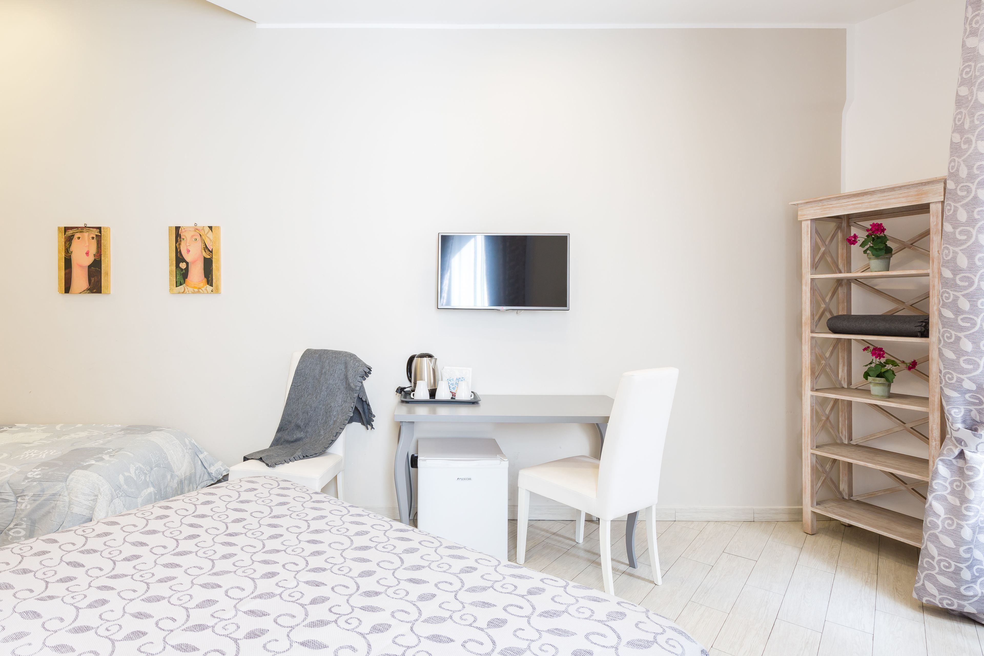 A bedroom with a bed, a desk, a chair, a TV, and a bookshelf.