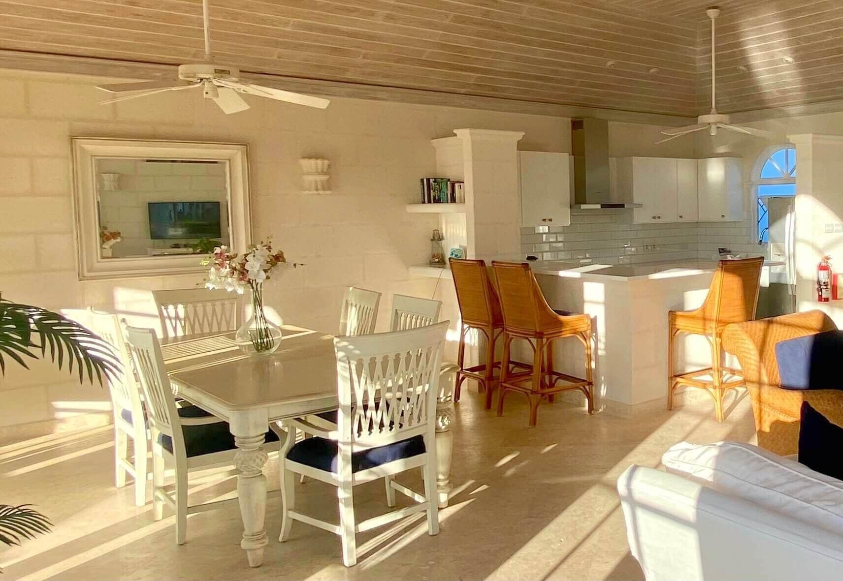 Una habitación luminosa e soleada con una mesa de comedor, sillas, un sofá y una zona de cocina.