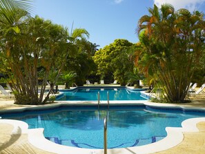 A swimming pool with clear blue water, surrounded by palm trees and lounge chairs. - Royal Villa by Island Villas (Westmoreland)
