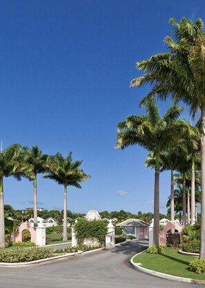 A residential street with palm trees, a curved road, and houses with pink and white exteriors. - Royal Villa by Island Villas (Westmoreland)