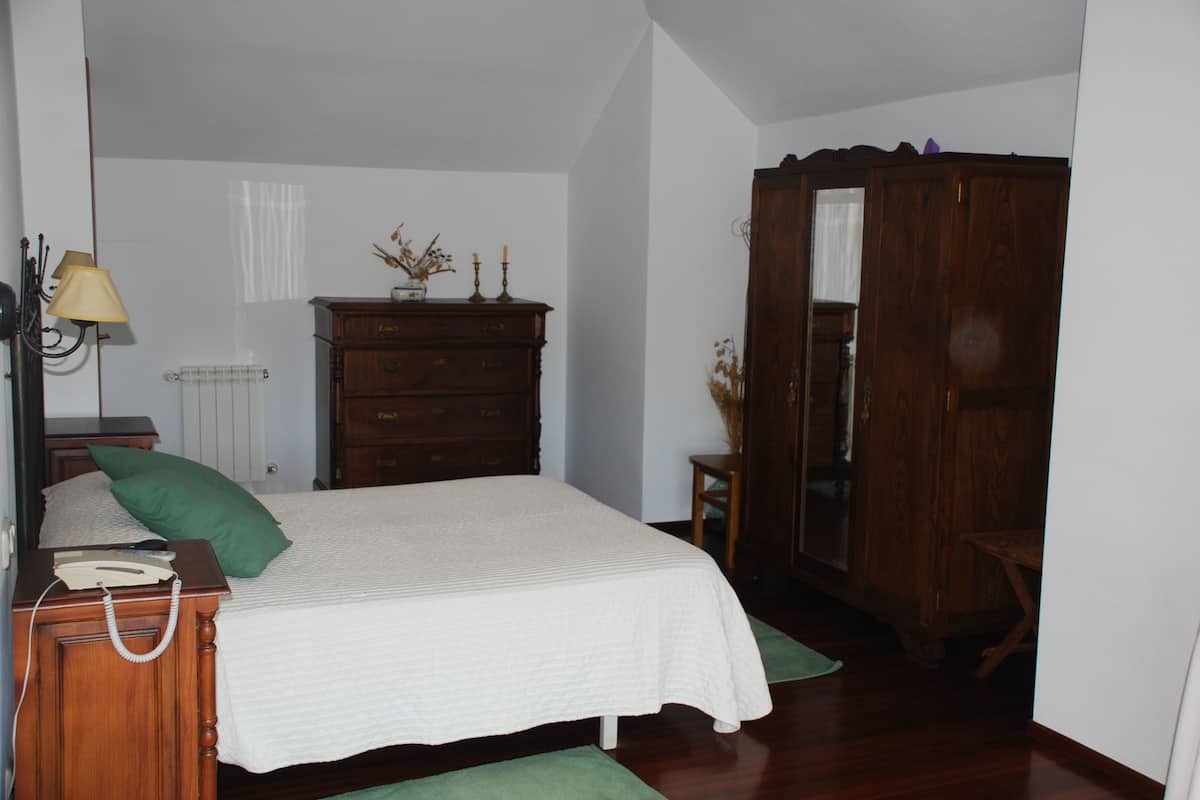 A bedroom with a bed, dresser, nightstand, lamp, and wardrobe.