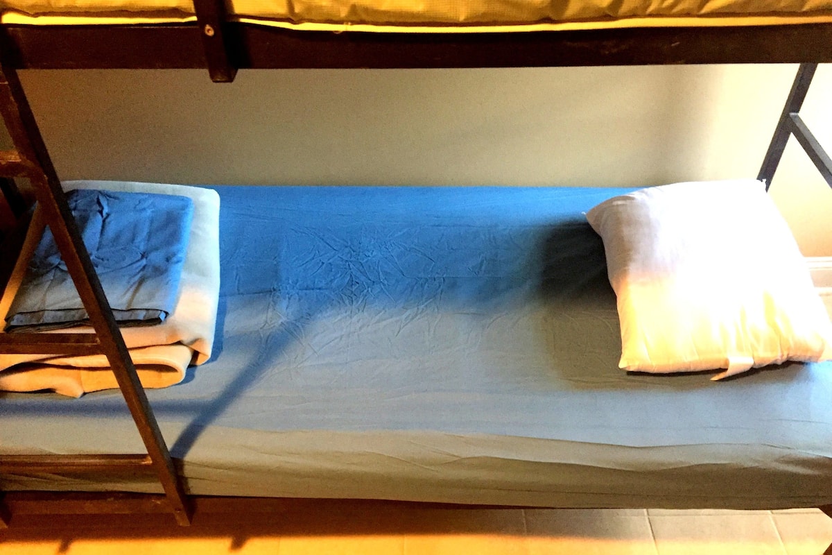 A bunk bed with a blue mattress and white pillows.