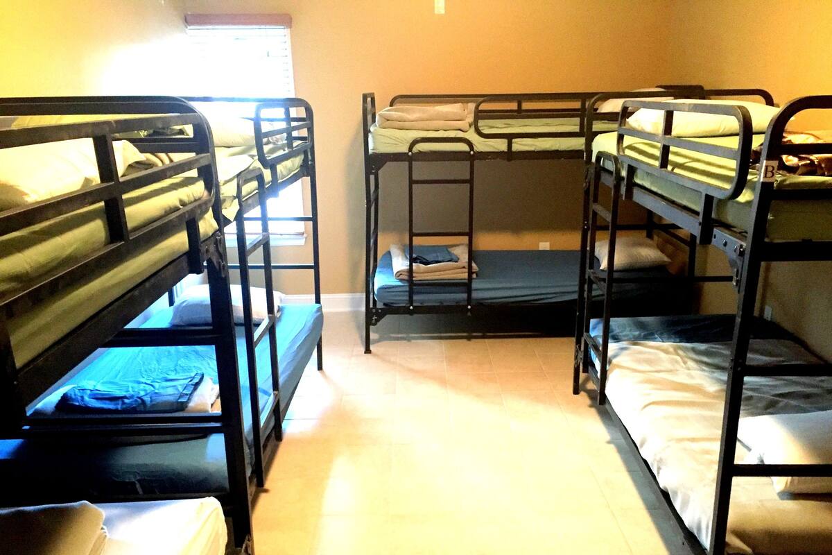A dormitory room with bunk beds arranged in two rows.