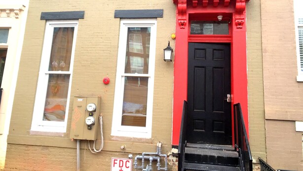 A building with a red door and a fire alarm on the wall. - DC International Hostel 2 (Washington)