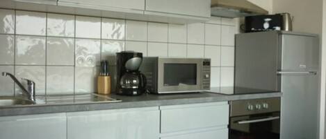 A kitchen with white cabinets, a microwave, a coffee maker, and a refrigerator.