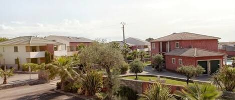 A residential area with multiple houses, a parking lot, and well-maintained landscaping including palm trees and shrubs.