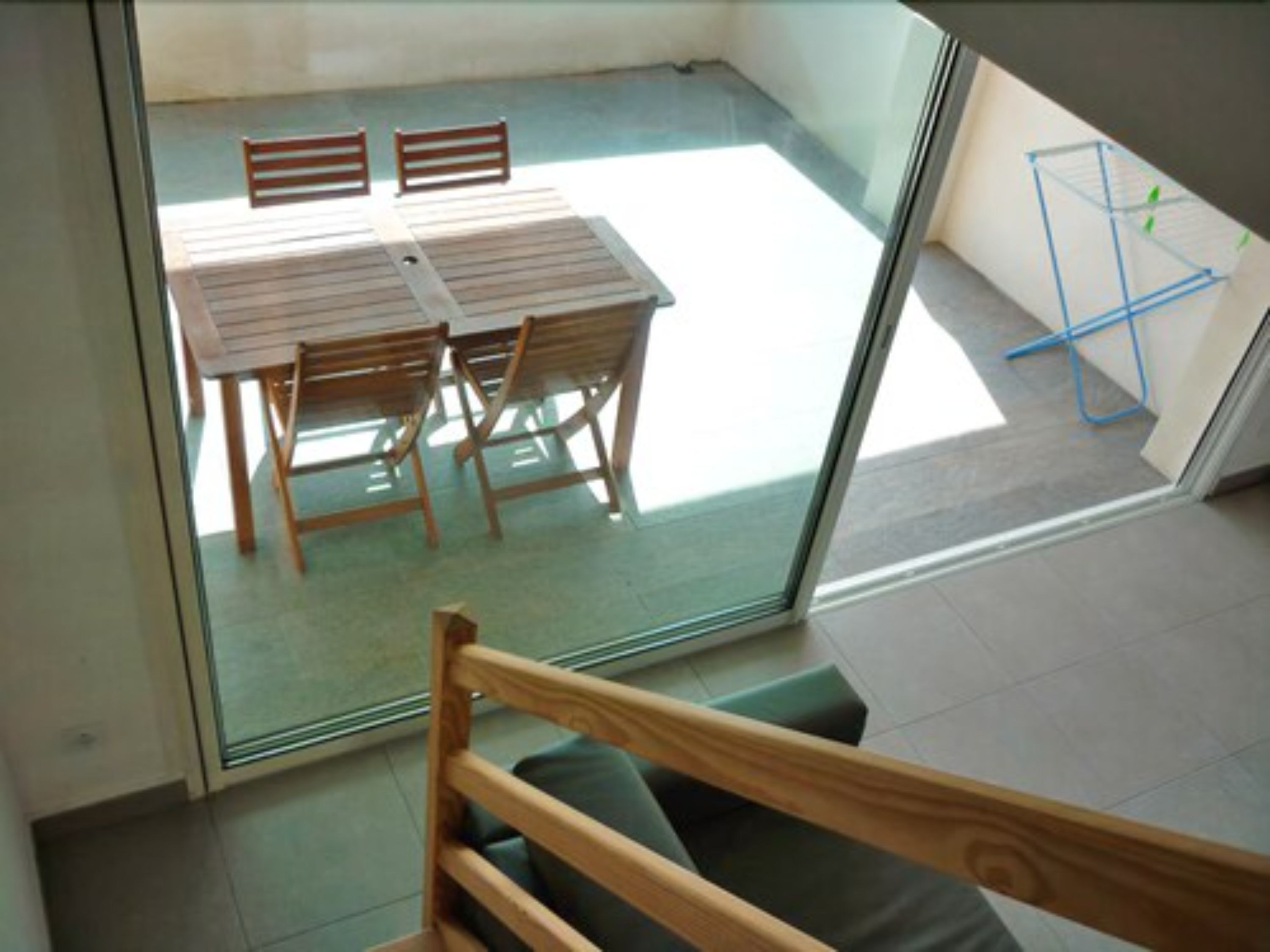 A room with a glass door leading to a balcony with a table and chairs.
