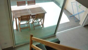 A room with a glass door leading to a balcony with a table and chairs.