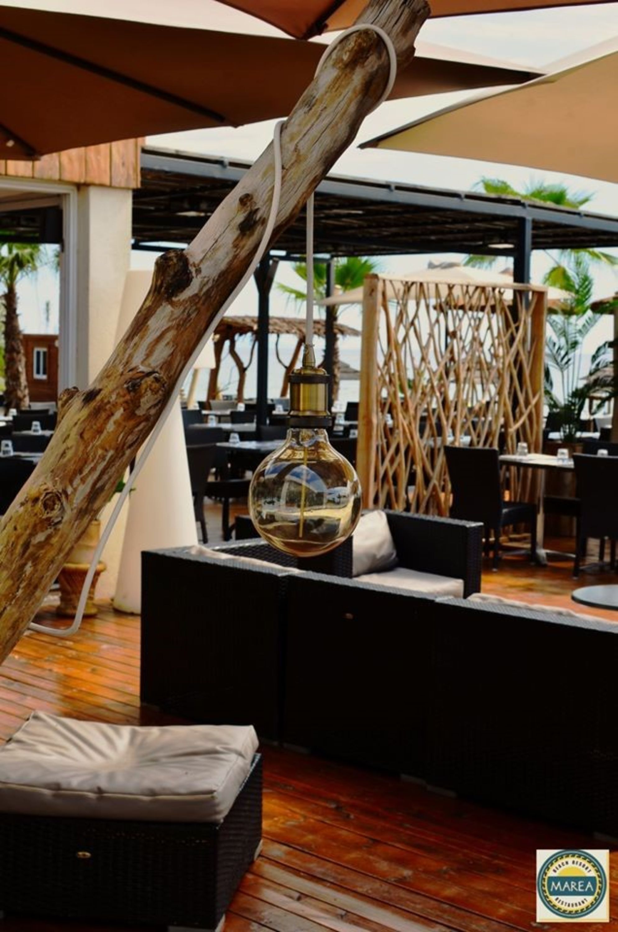 An outdoor seating area with a wooden structure, a glass bottle lamp, and a wicker basket.