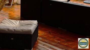 An outdoor seating area with a wooden structure, a glass bottle lamp, and a wicker basket.