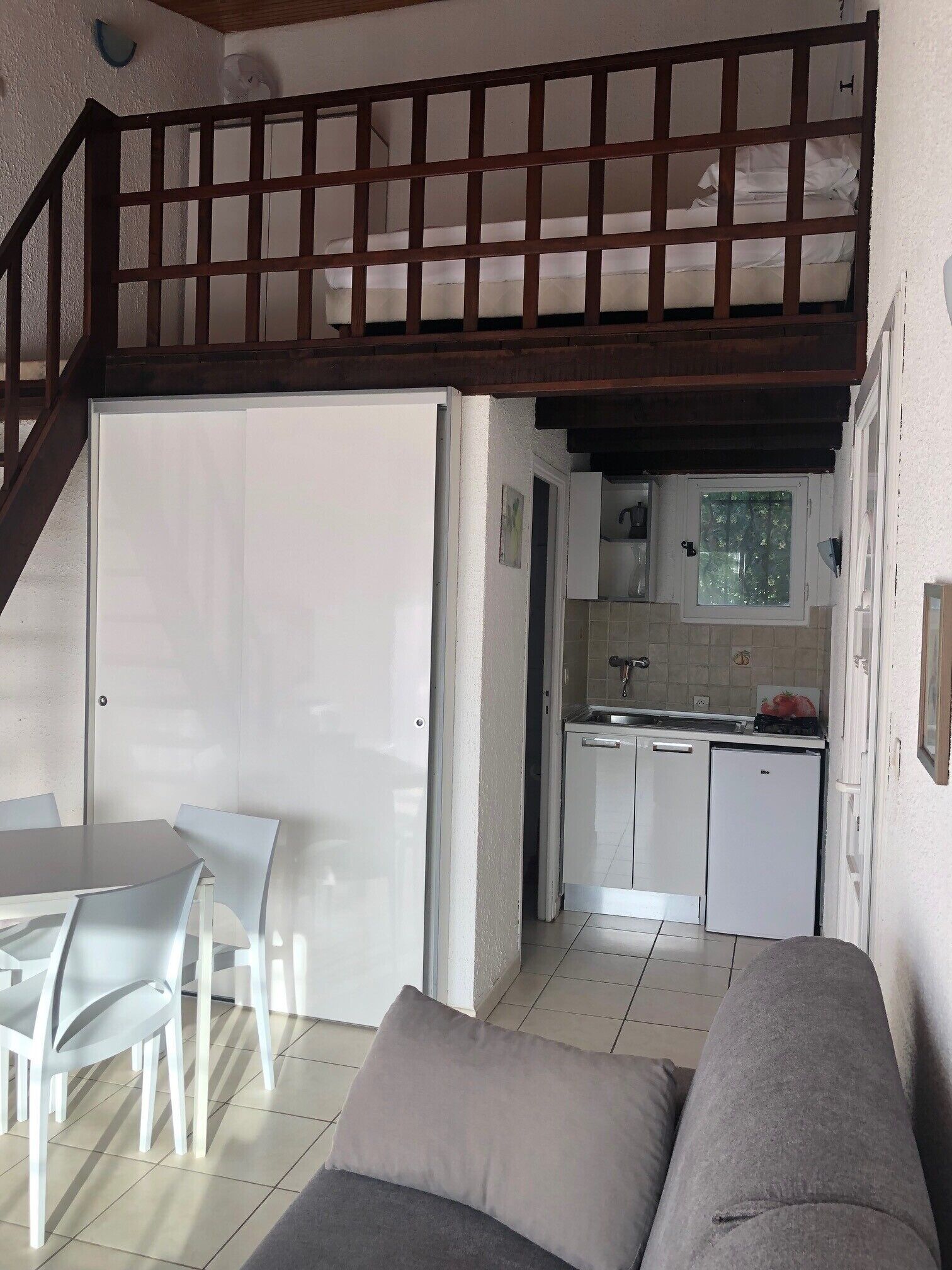 A compact living space with a dining area, kitchenette, and a staircase leading to an upper level.