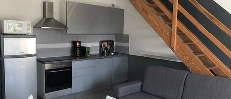 Una cocina moderna con armarios grises, horno integrado y cafetera.