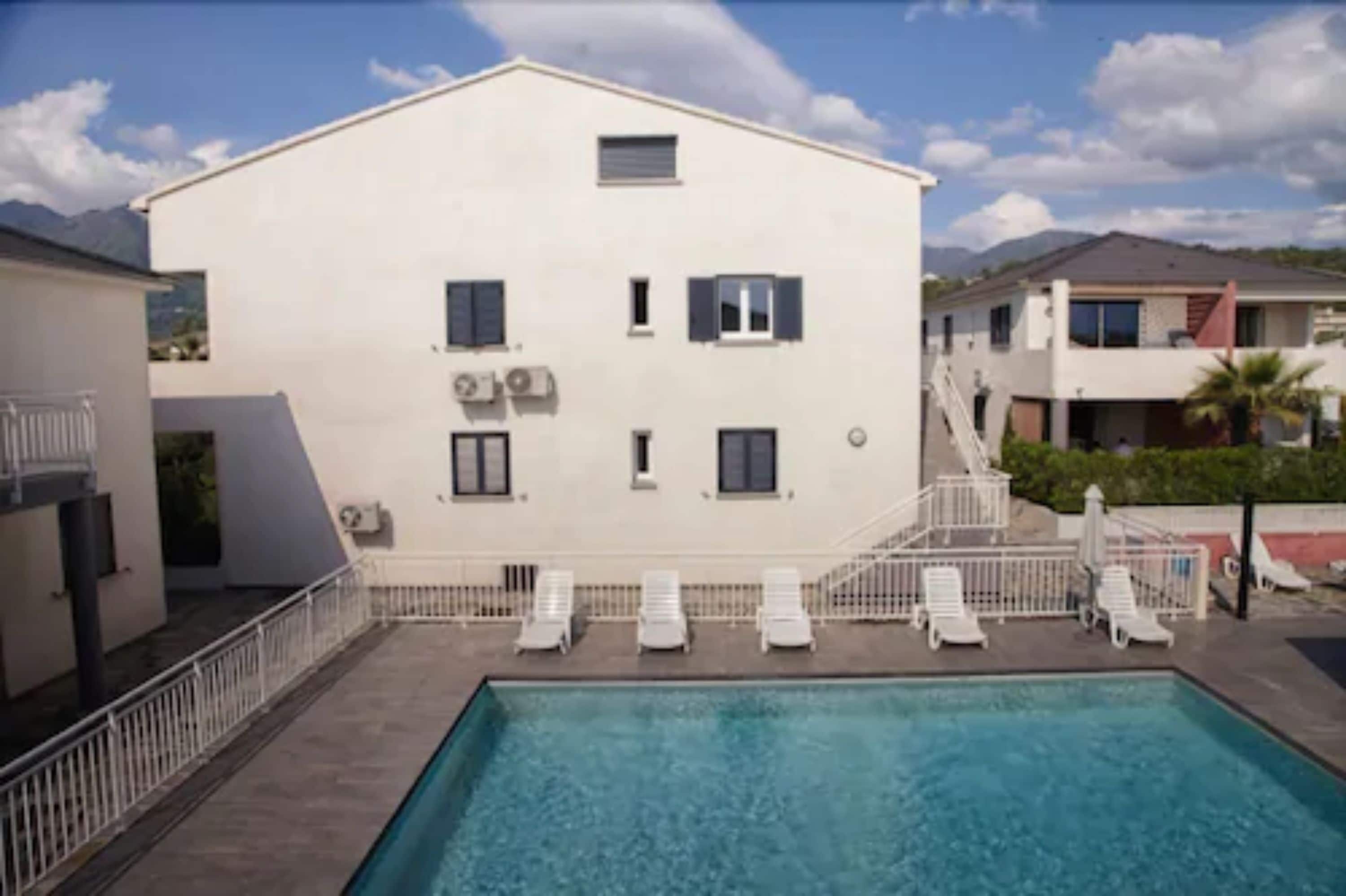 Um edifício com piscina, fachada branca e várias janelas.