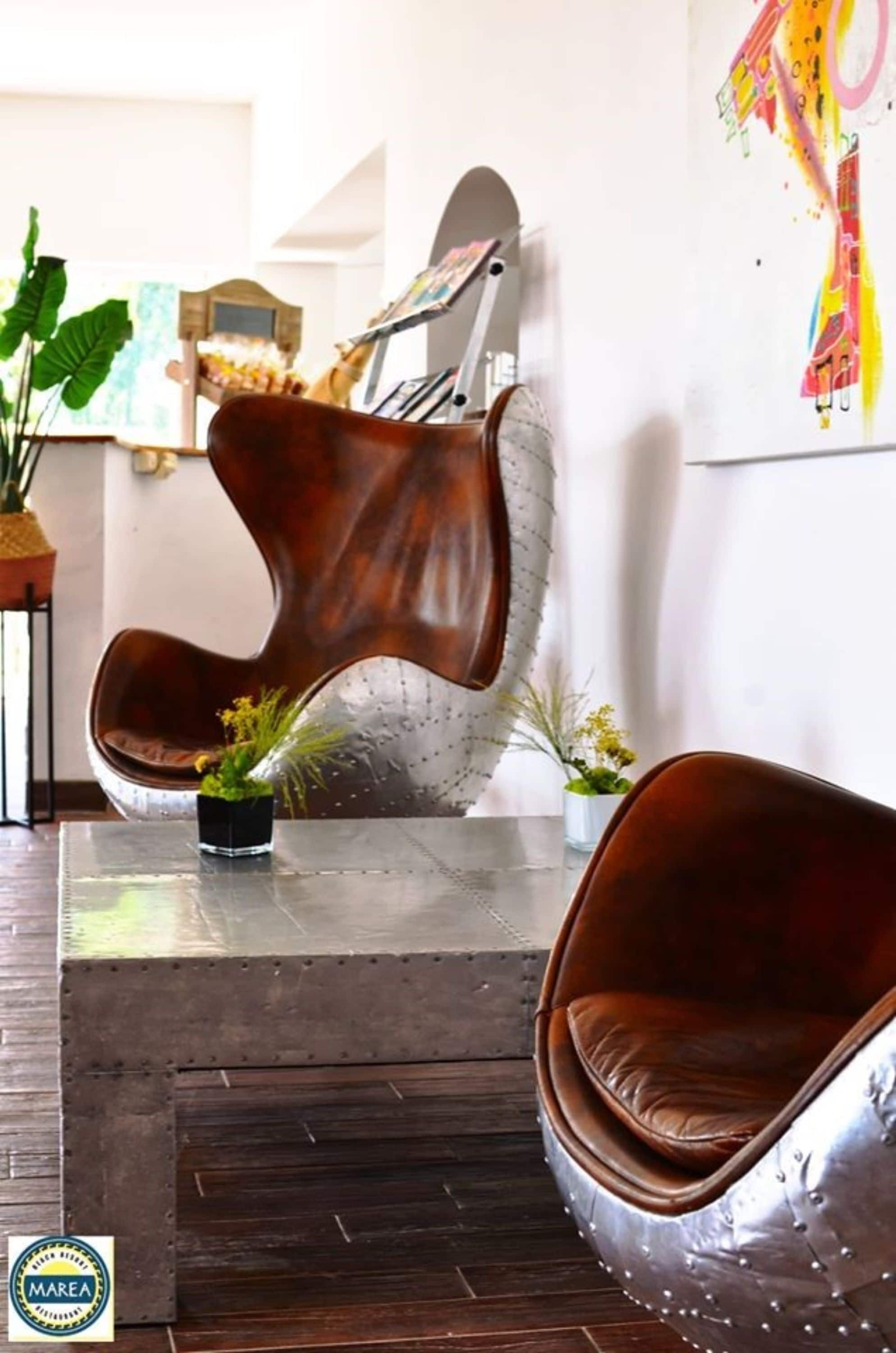Una sala de estar moderna con un sillón escultural único, una mesita con una planta y un cuadro abstracto colorido en la pared.
