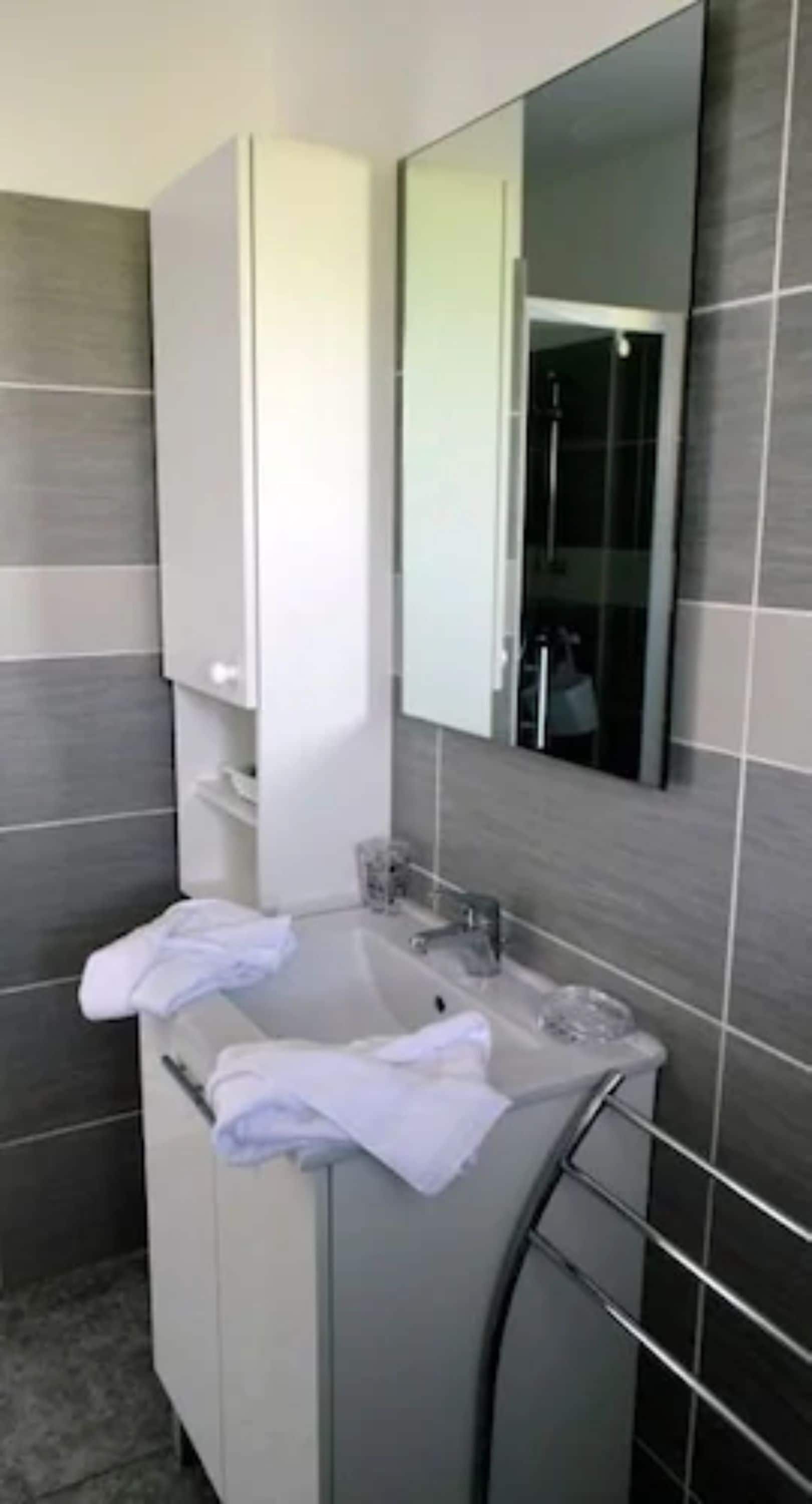 A modern bathroom with a white vanity, a large mirror, and a glass shower enclosure.
