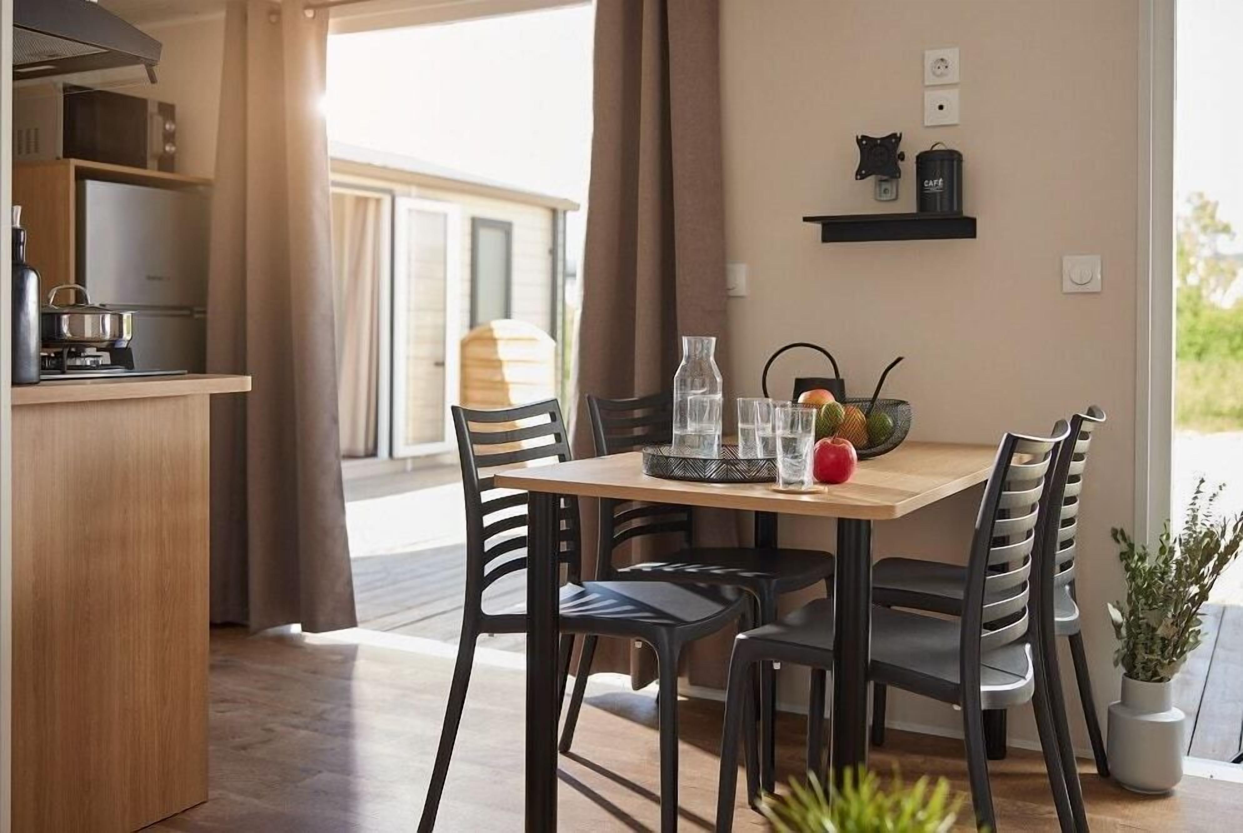 A dining area with a wooden table, black chairs, and a kitchen area with a stove and cabinets.