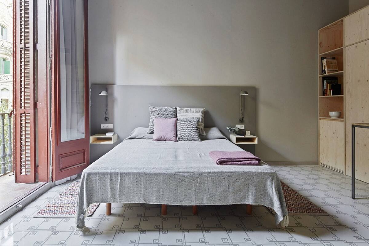 Een slaapkamer met een bed, nachtkastjes, een kledingkast van hout en een vloer met een patroon.