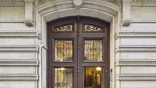 A grand entrance with a dark brown door featuring ornate metalwork and glass panels. - Casa Abamita (Barcelona)