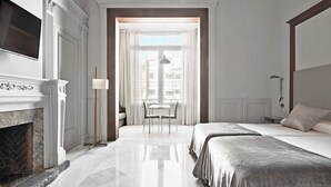 A hotel room with a fireplace, a bed, a desk, and a window with curtains. - Casa Abamita (Barcelona)