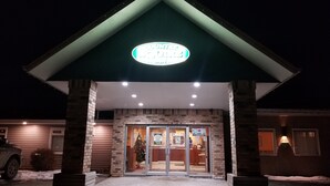 A hotel entrance with a green roof, illuminated sign, and a Christmas tree. - Moosomin Country Squire Inn (Moosomin)