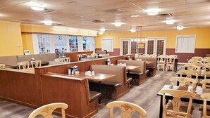 A restaurant with booths and tables, a counter, and a clock on the wall. - Moosomin Country Squire Inn (Moosomin)