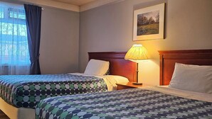 A hotel room with two beds, a nightstand, a lamp, a framed picture on the wall, and a window with curtains. - Moosomin Country Squire Inn (Moosomin)