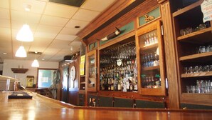 A bar area with wooden shelves, hanging lights, and a variety of bottles and glasses. - Moosomin Country Squire Inn (Moosomin)
