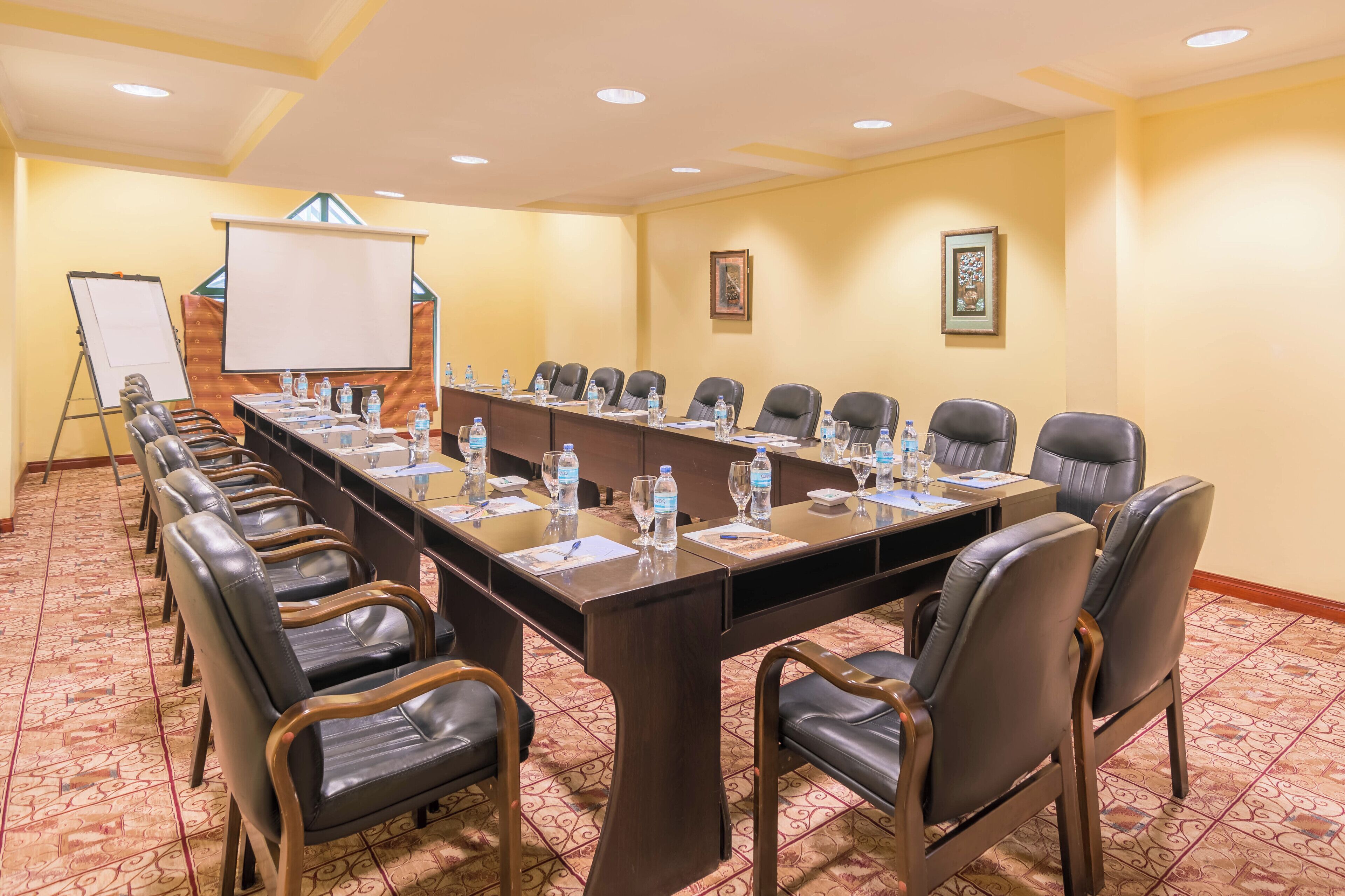 A conference room with a long table, leather chairs, water bottles, and a whiteboard.