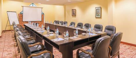 A conference room with a long table, leather chairs, water bottles, and a whiteboard.