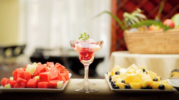 Un tavolo con tre vassoi di frutta e un bicchiere di cocktail di frutta.
