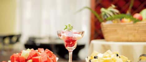 A table with three fruit platters and a glass of fruit cocktail.