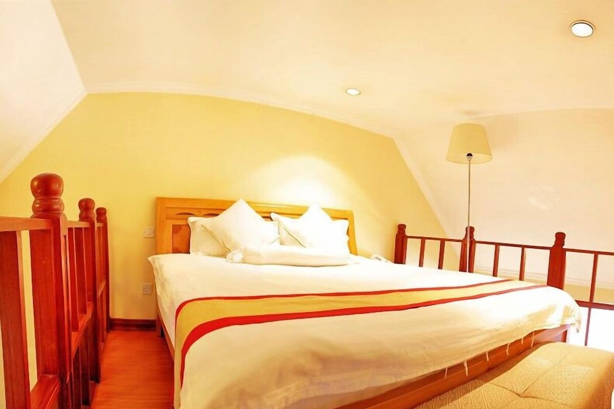 Un lit bien fait dans une pièce dont le plafond est en pente et qui est doté d’une tête de lit en bois.