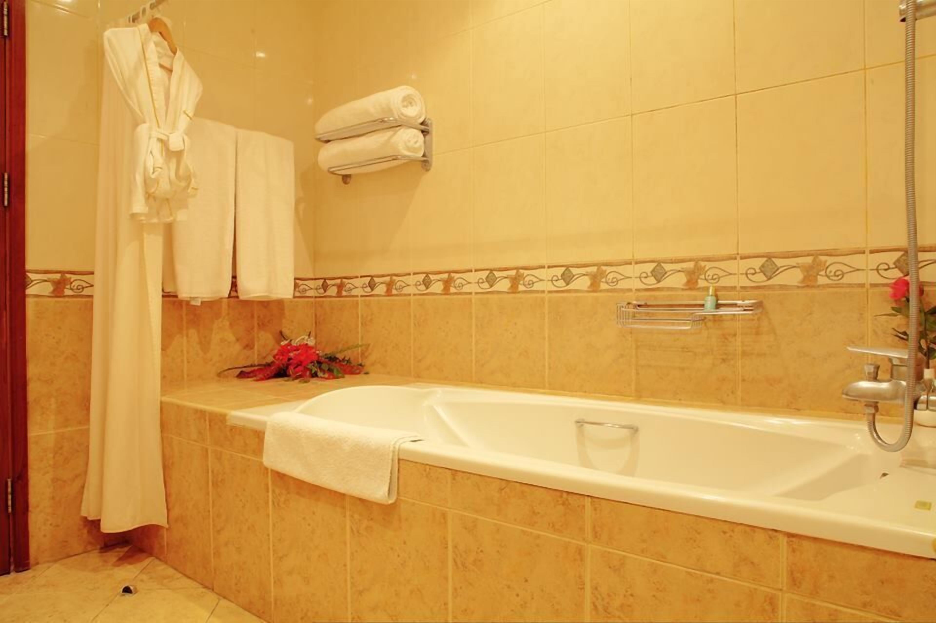 A bathroom with a bathtub, a shower, and a towel rack with towels.