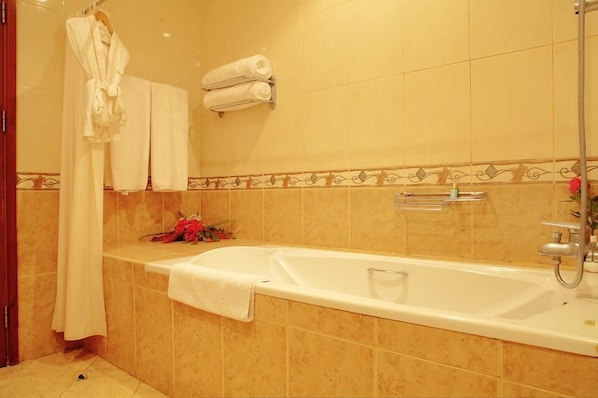 Un baño con bañera, ducha y toallero con toallas.