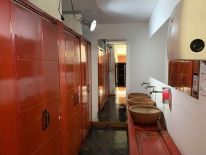 Um corredor com armários de madeira, bebedouro e pia com espelho.