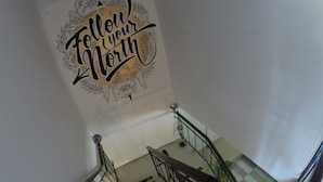 Een trap met een leuning en een muur met een decoratief bord waarop staat 'Follow your North'.