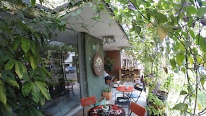 Een terras met tafels en stoelen, omringd door potplanten en groen.