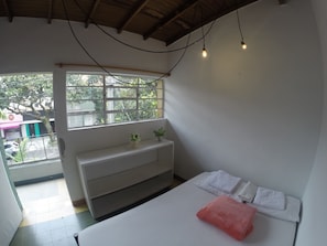 Una habitación con una cama, un banco, una ventana y vistas al exterior.