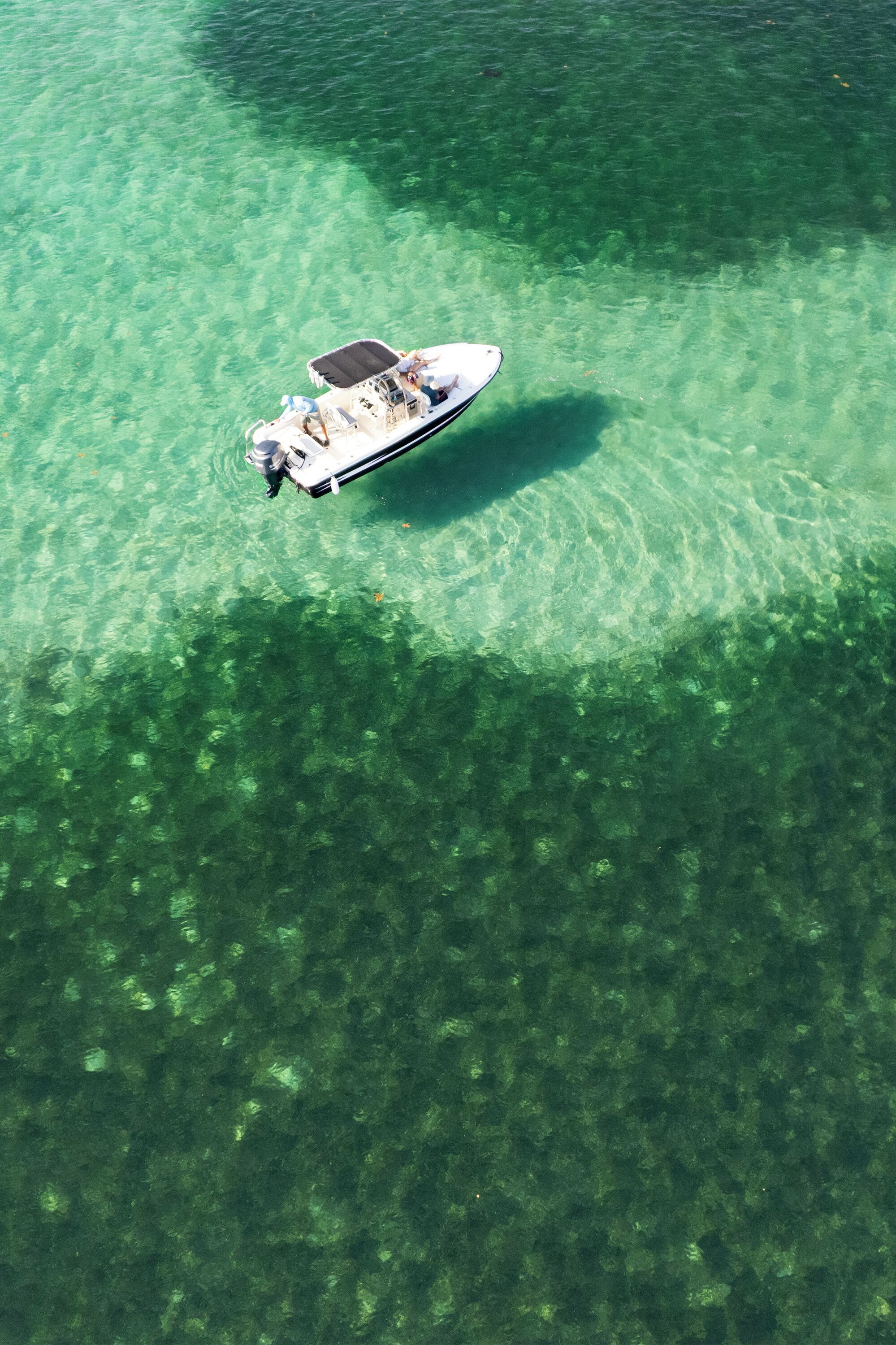 A boat on clear water with a shadow on the surface.