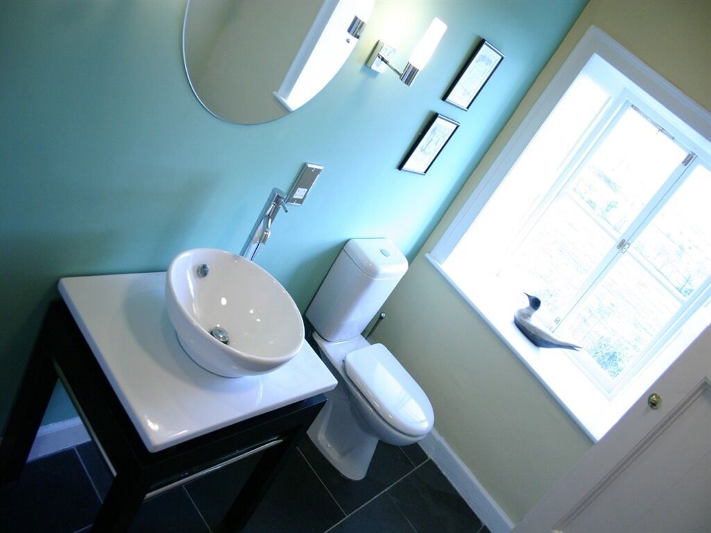 A bathroom with a white sink, a toilet, and a window.