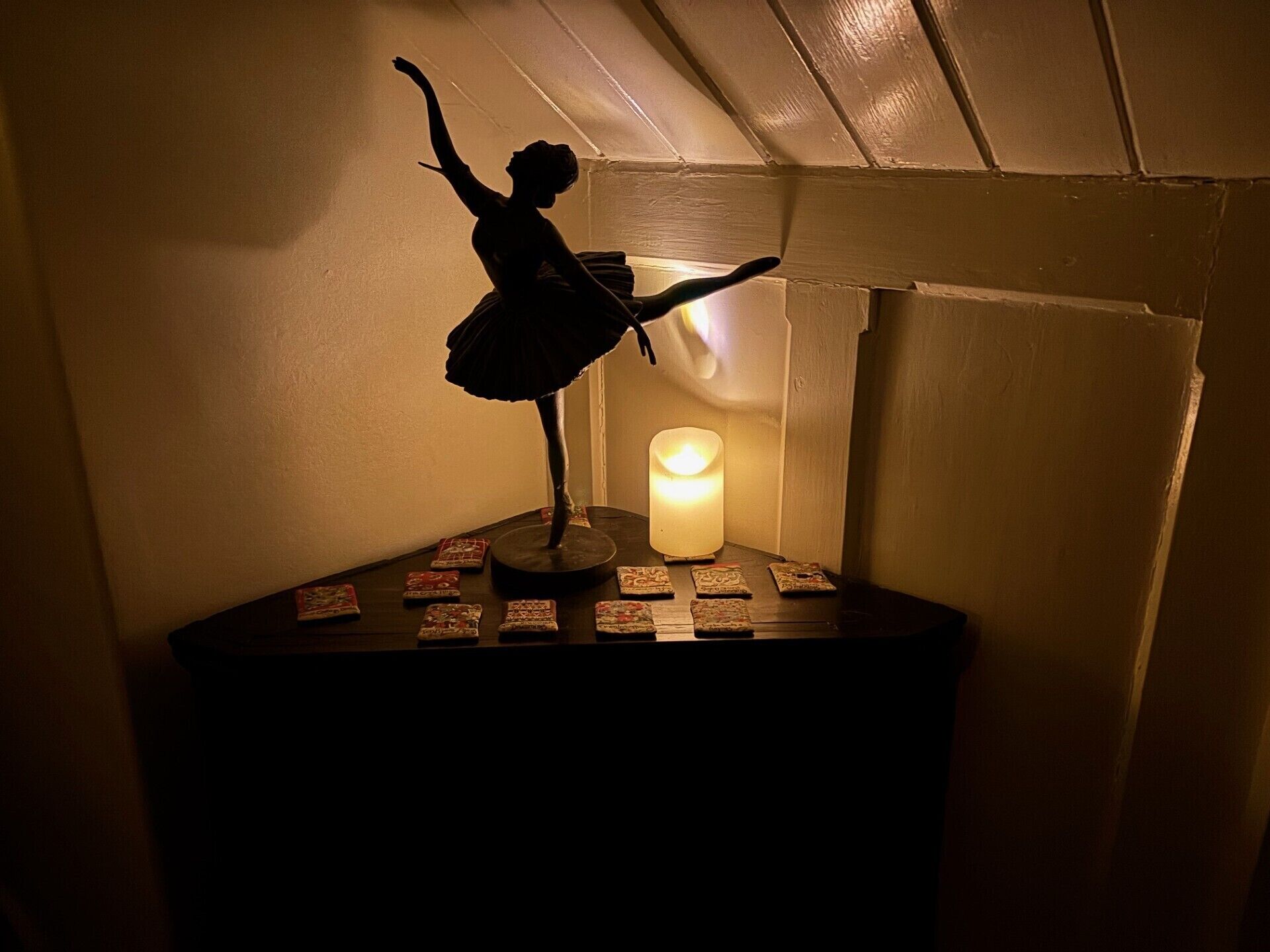 A silhouette of a dancer on a pedestal with a lit candle and playing cards.