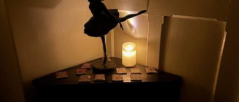 A silhouette of a dancer on a pedestal with a lit candle and playing cards.
