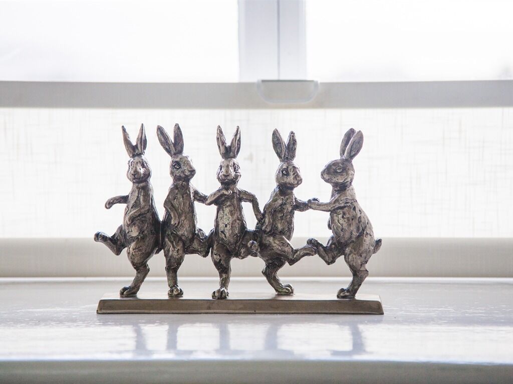 A metal sculpture of rabbits on a shelf.