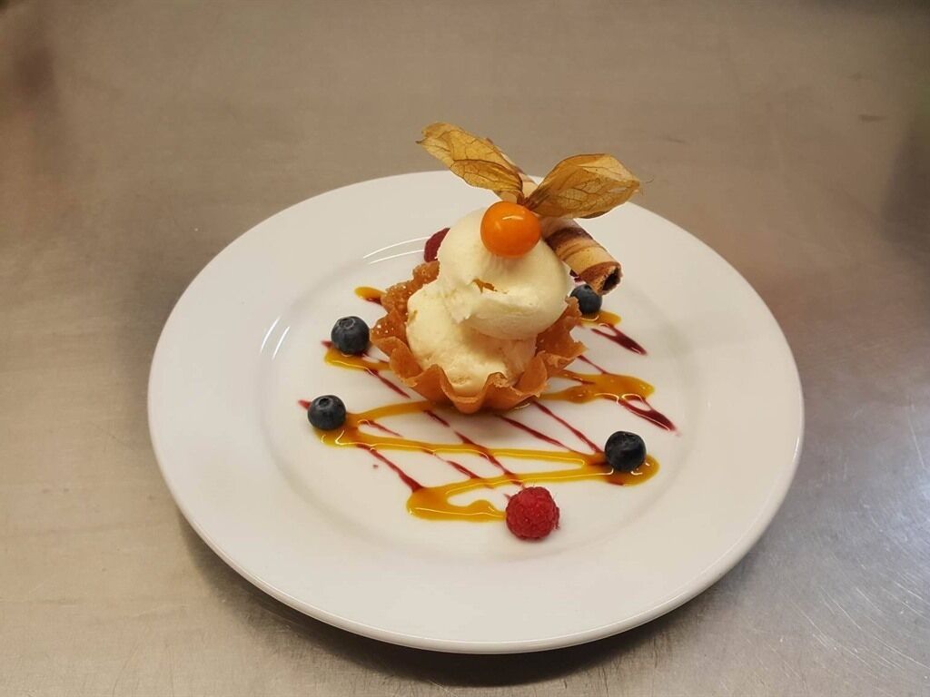 A dessert on a white plate with a caramel drizzle and fruit garnishes.