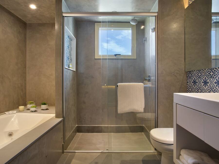 Un baño moderno con ducha de vidrio, bañera y retrete.